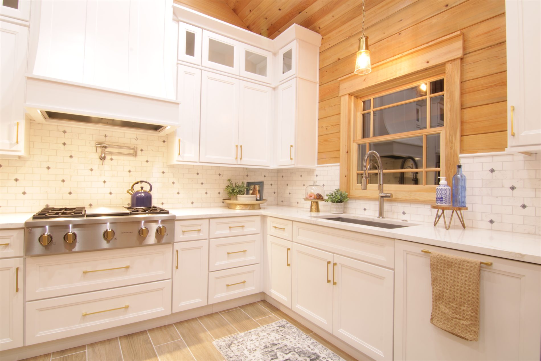 White kitchen cabinetry, sink, backsplash, and wood wall detail in an Apopka custom log cabin