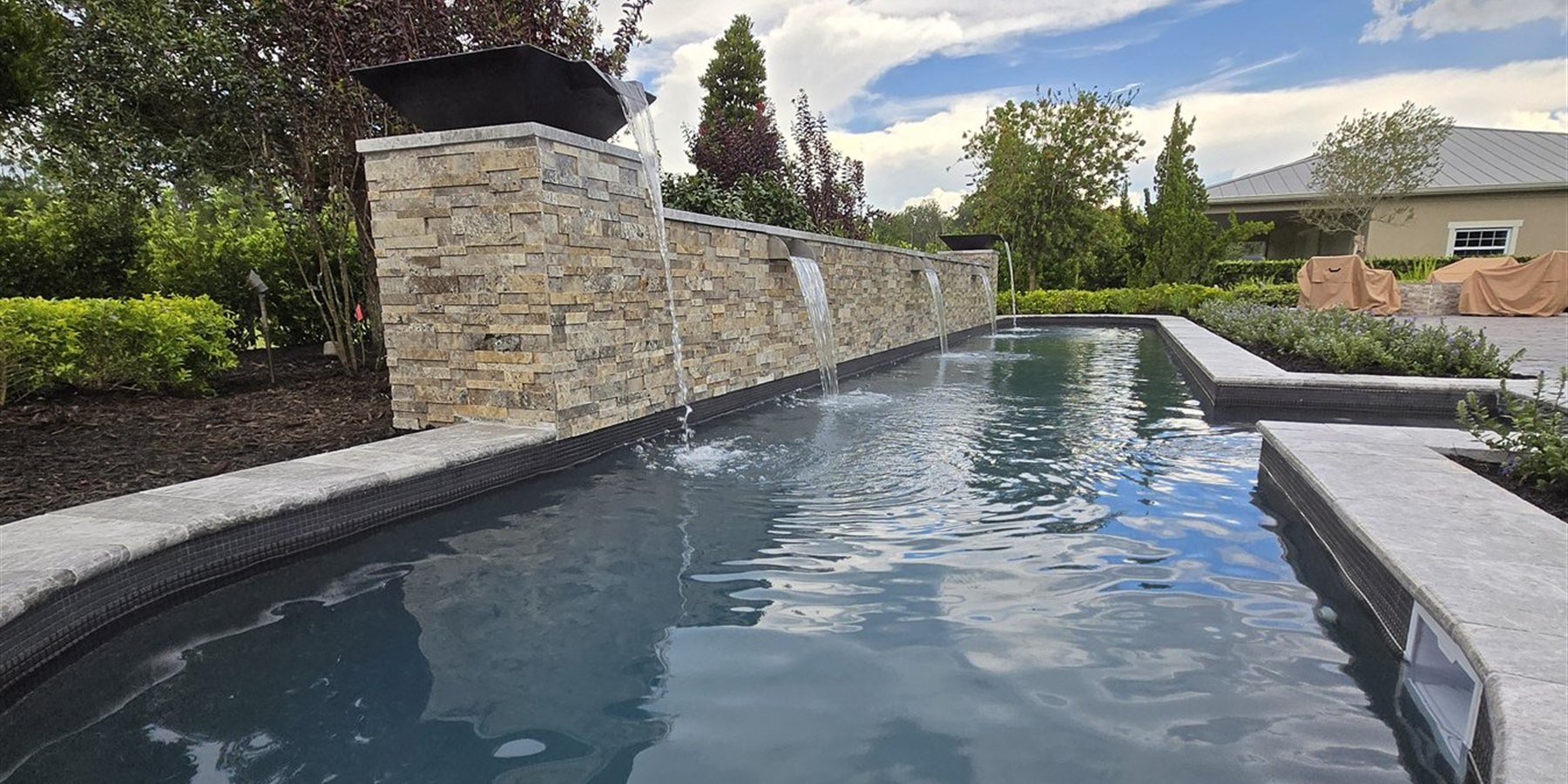 Wide pool view with stone water feature and finished deck surfaces